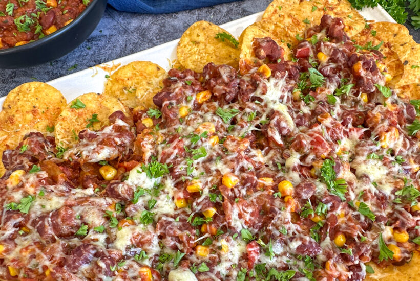 Slow Cooker Vegetarian Chili Nachos covered in cheese and parsley
