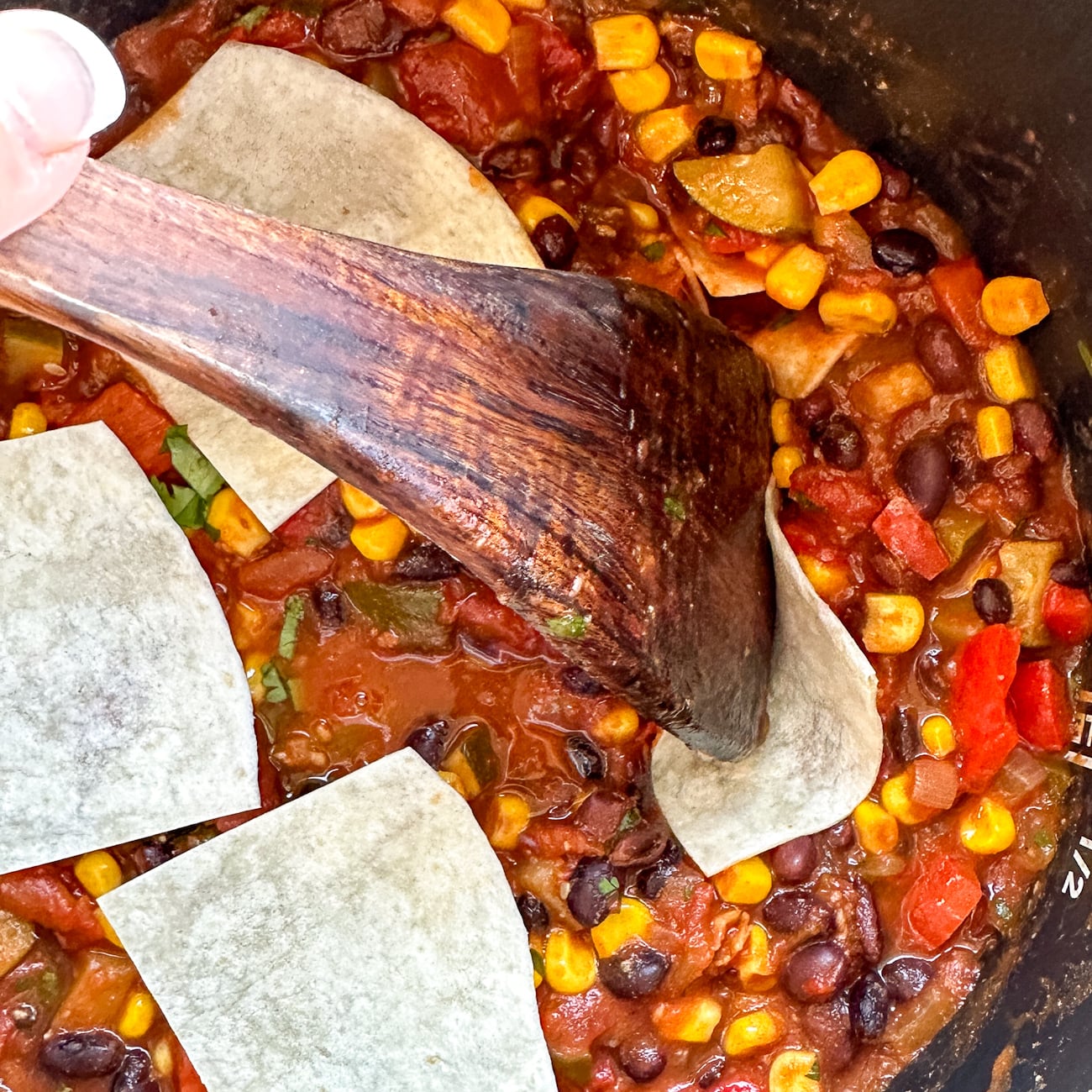 pressing the tortillas into the enchilada casserole