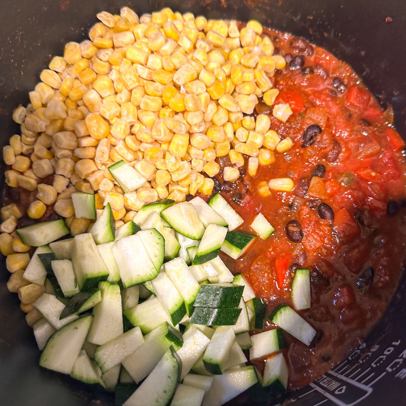 adding the corn and the zucchini to the slow cooker