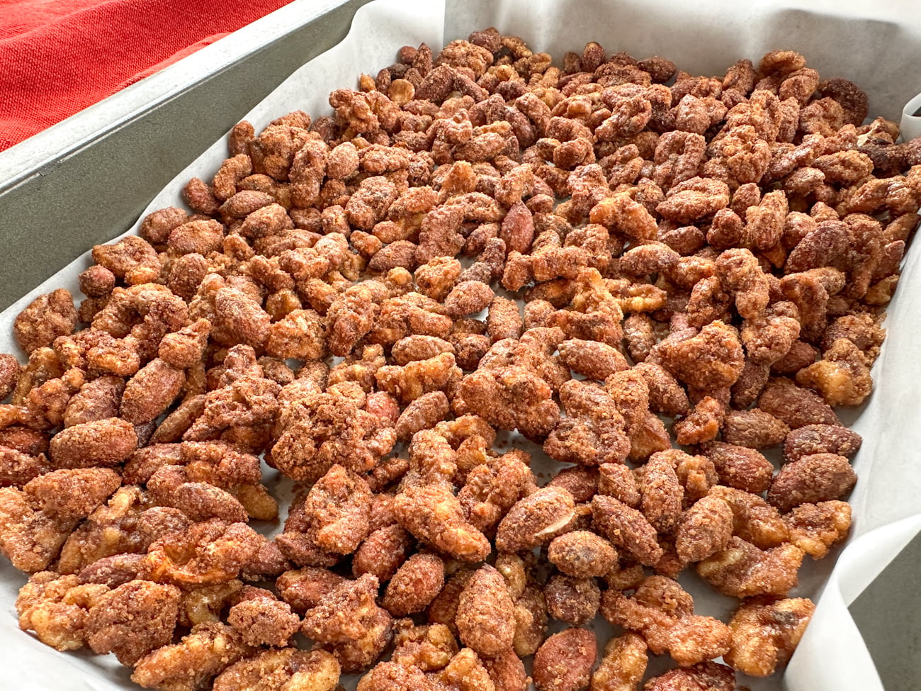 adding candied nuts to an oven tray after slow cooking