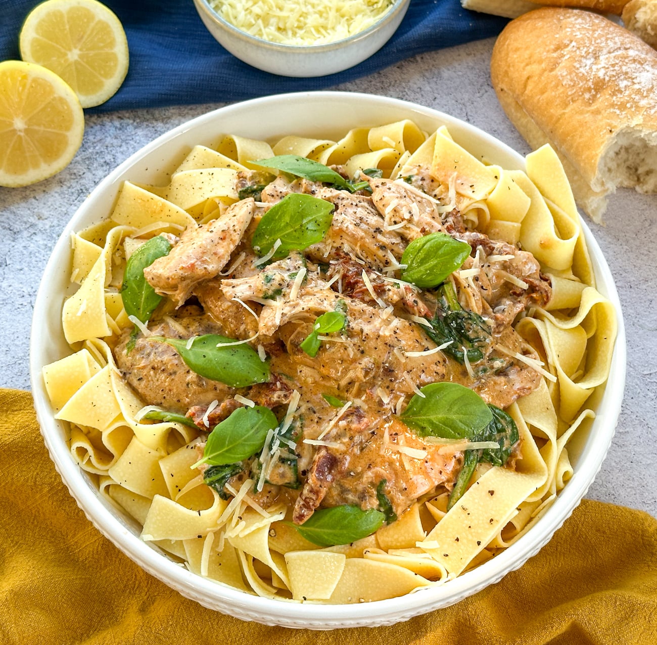 slow cooker creamy tuscan chicken served over pappardelle with lemon juice parmesan and crusty bread