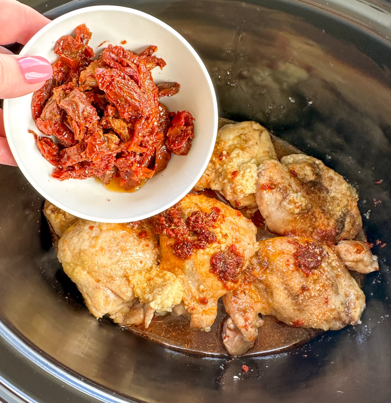 adding the sun-dried tomato to the slow cooker before cooking