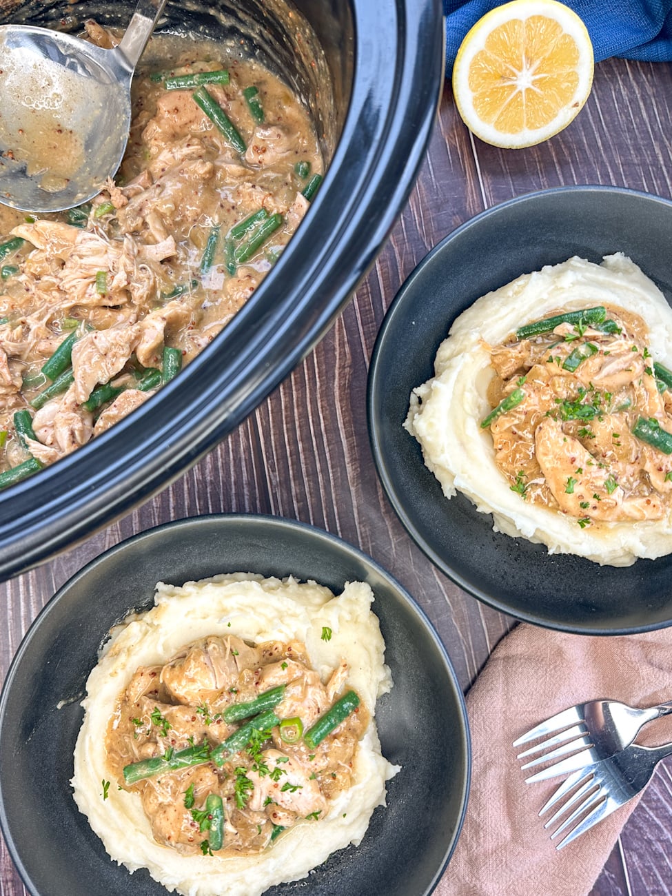 slow cooker with honey mustard chicken and two bowls served over mashed potato