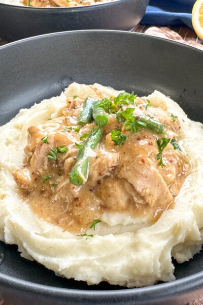 plate of mashed potato topped with honey mustard chicken