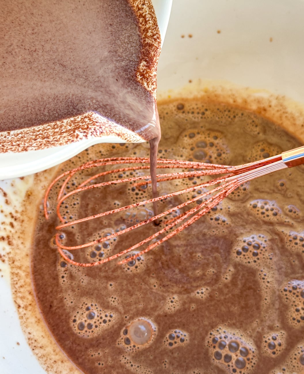 whisking the chocolate slowly into the egg yolk mixture to make custard