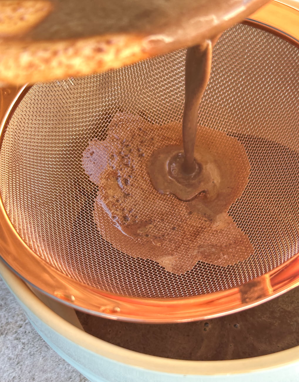 Pouring the chocolate custard mixture through a sieve into a jug