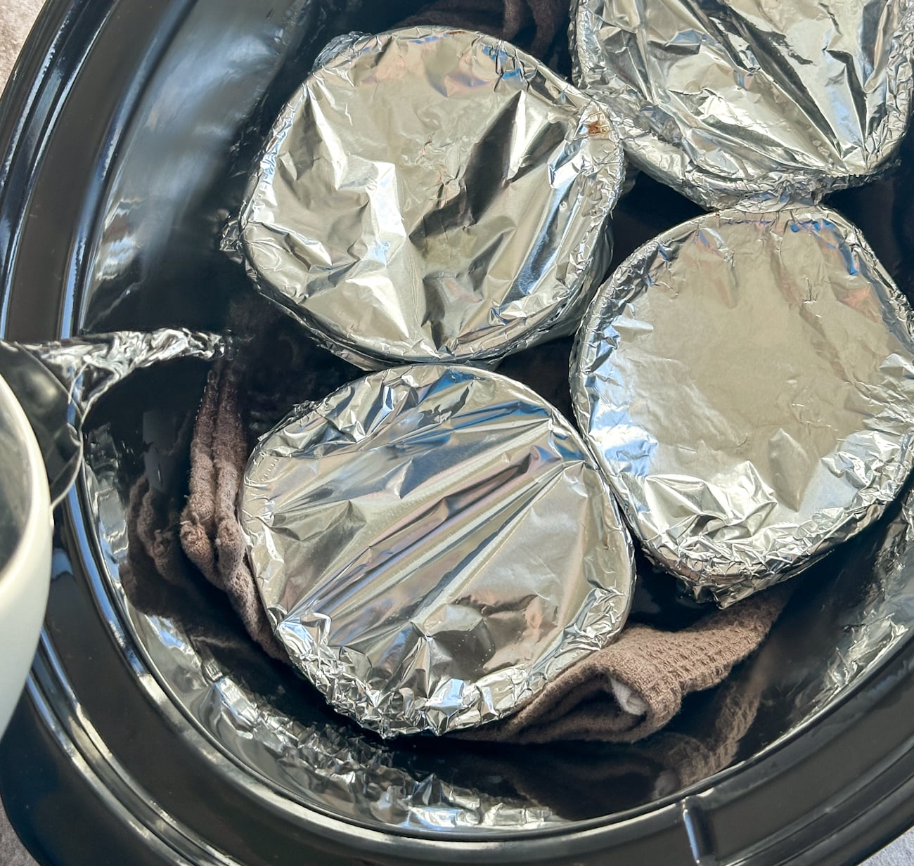 pouring hot water into the slow cooker to create a water bath for chocolate puddings