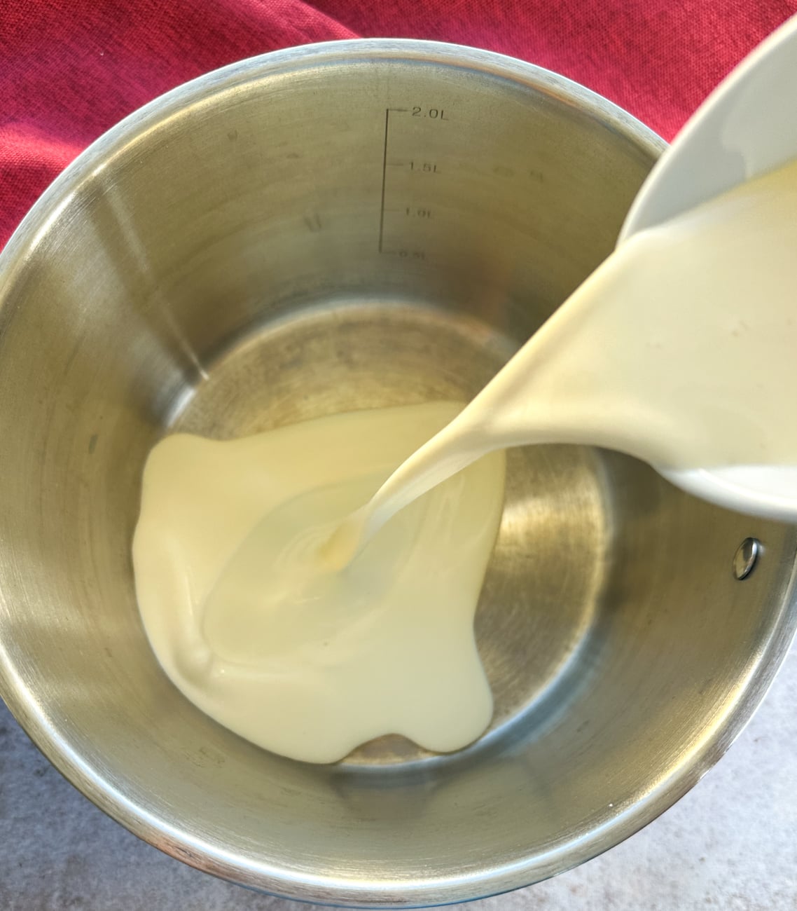 pouring cream into a saucepan to heat