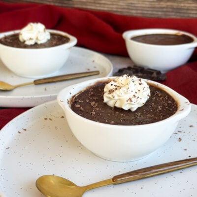 Slow Cooker Silky Chocolate Pots in white ramekins with cream and shaved chocolate