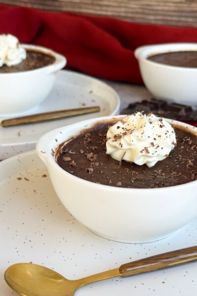 Slow Cooker Silky Chocolate Pots in white ramekins with cream and shaved chocolate