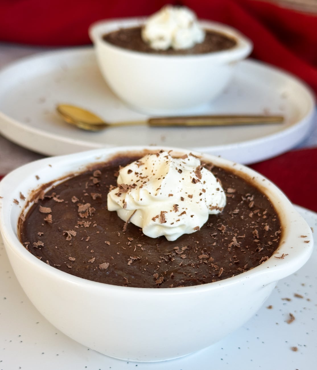 Silky chocolate pots in white ramekins with a dollop of whipped cream and chocolate shavings