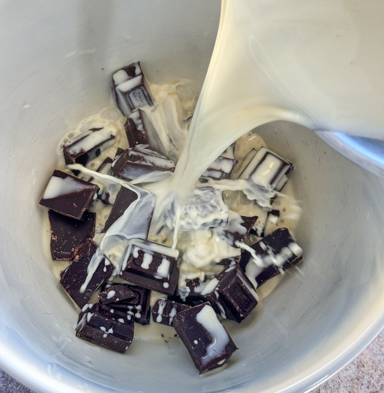 pouring hot cream and milk over chocolate