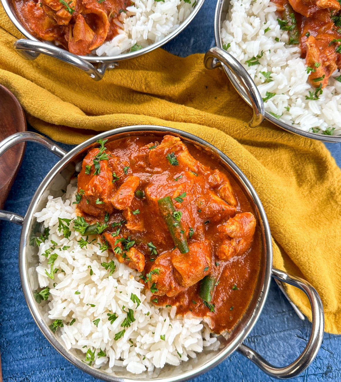 bowls of rice with a tomato chicken curry spooned over the top