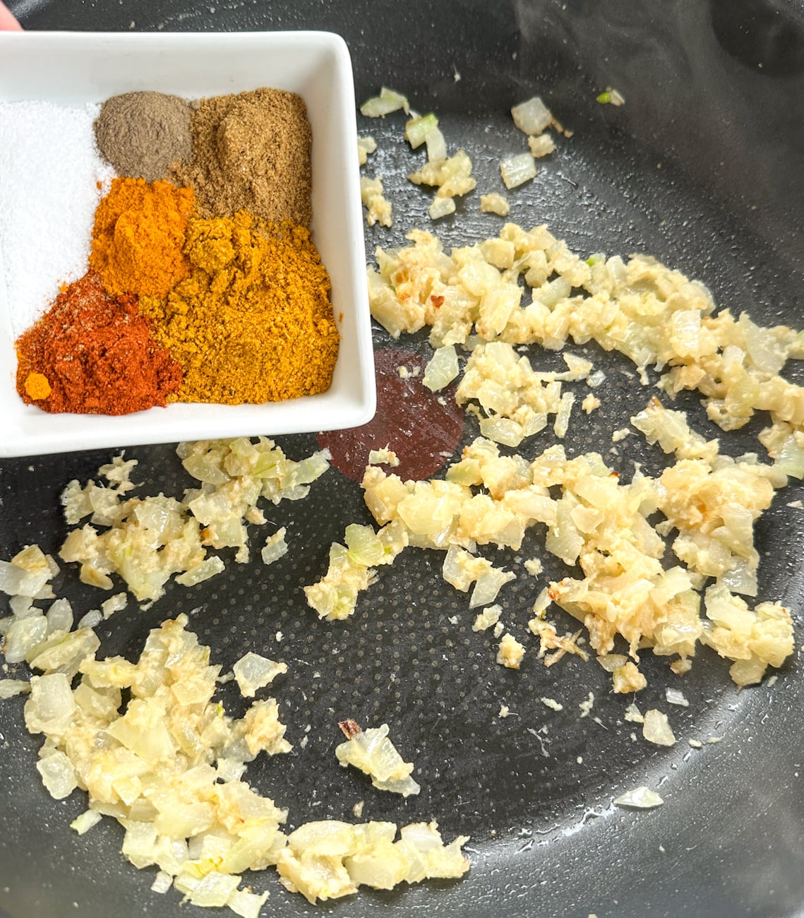 adding spices to sauteed onion and garlic