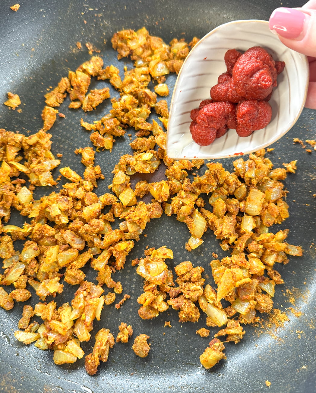 Add tomato paste to the spices and onion and cook off until fragrant