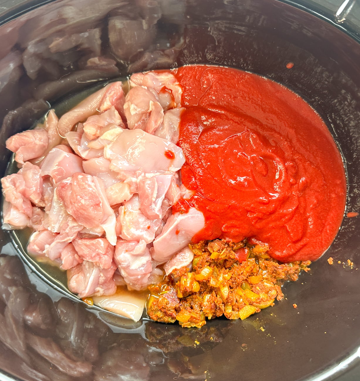 all of the ingredients for a chicken tomato curry in the slow cooker