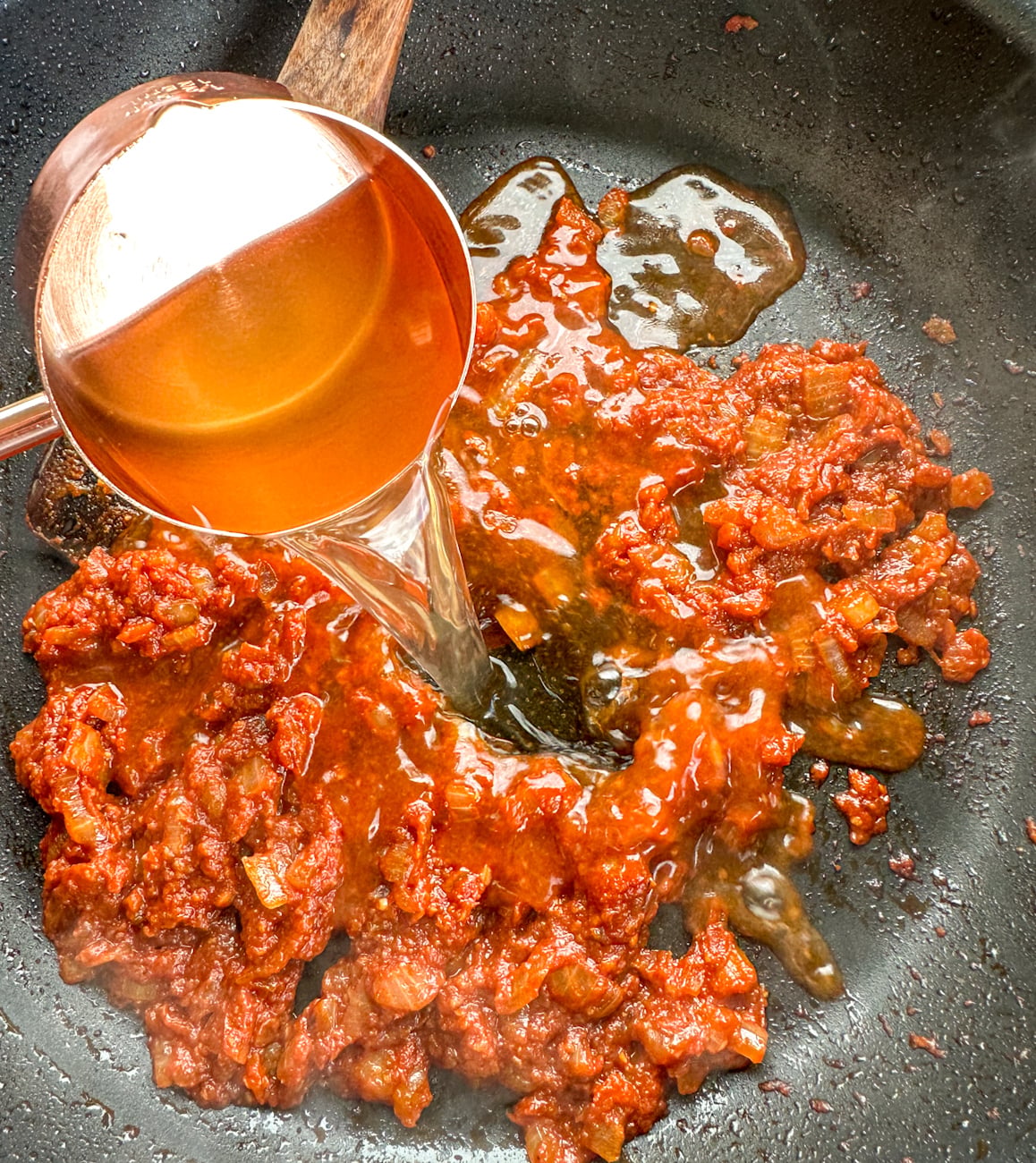 adding stock to the tomato paste base