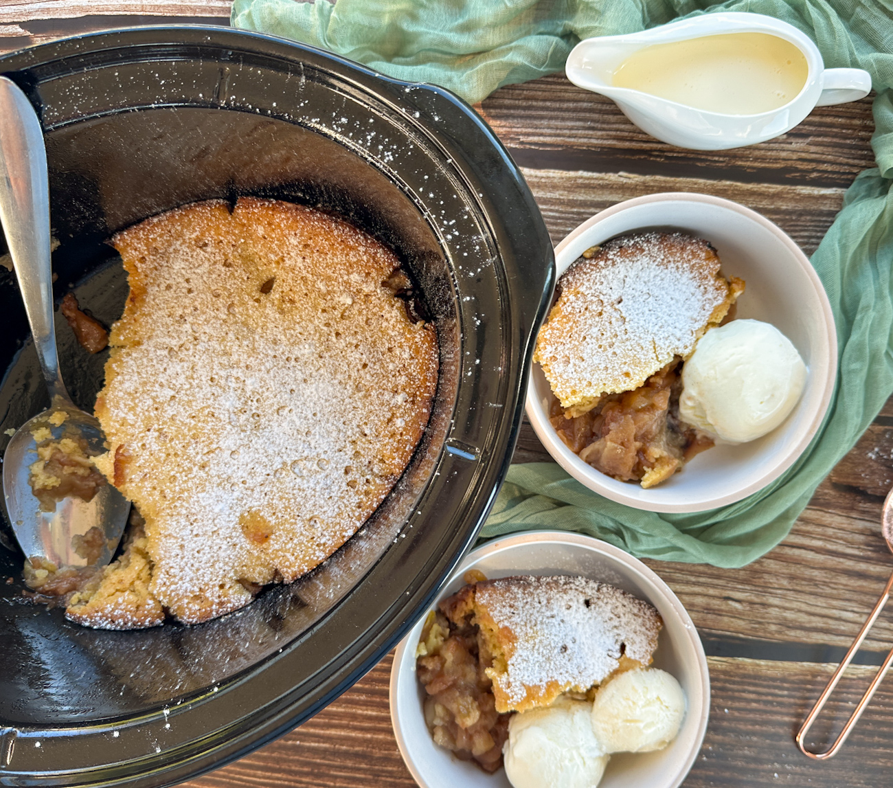 slow cooker with warm apple sponge pudding and two bowls served
