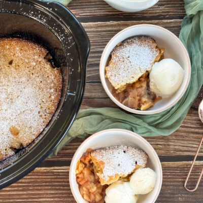 Slow cooker apple sponge pudding, served in two bowls with ice cream