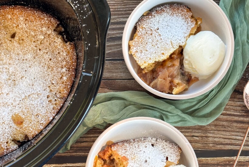 Slow cooker apple sponge pudding, served in two bowls with ice cream