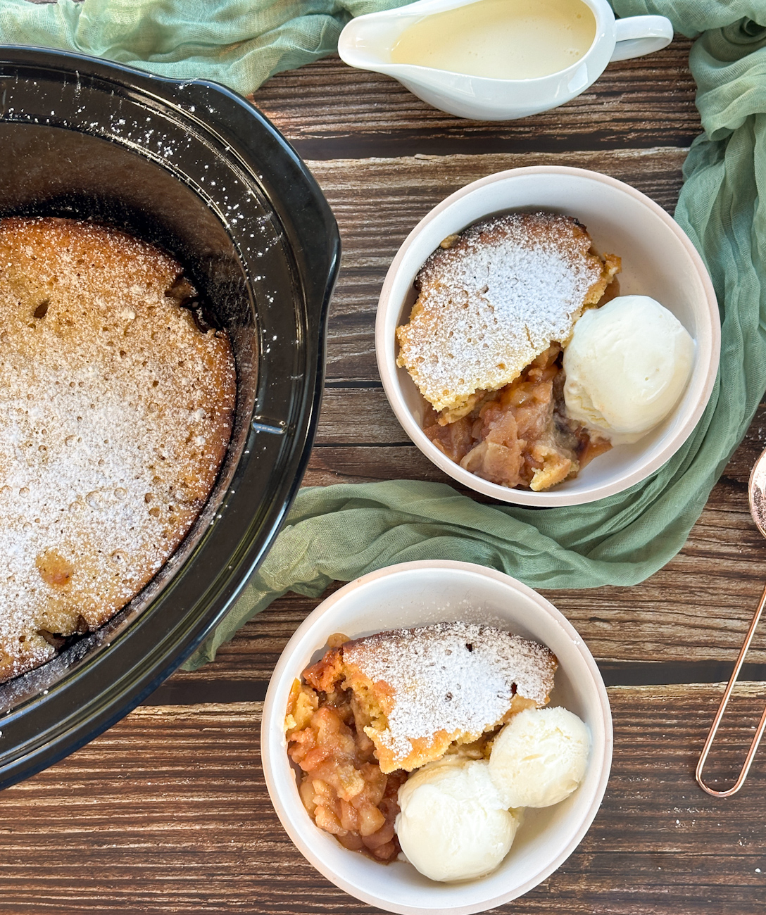 Slow cooker apple sponge pudding, served in two bowls with ice cream