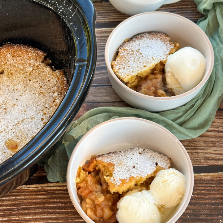serving apple sponge pudding from the slow cooker with ice cream in bowls