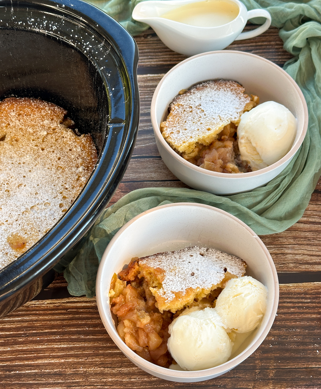 serving apple sponge pudding from the slow cooker with ice cream in bowls