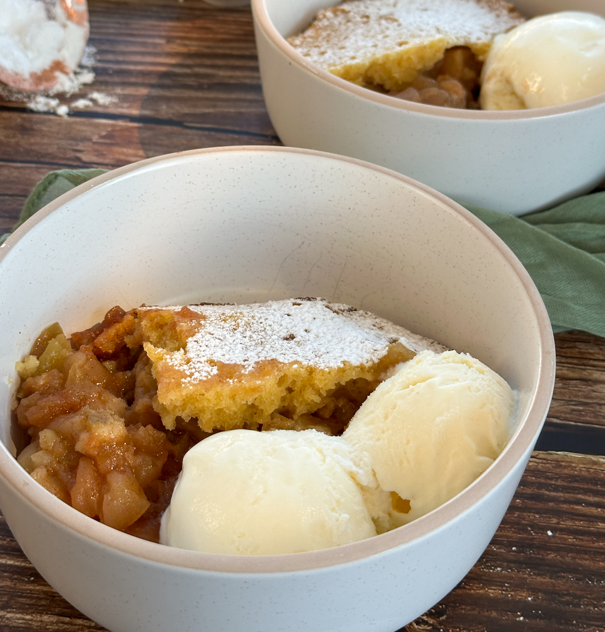 bowl of apple sponge pudding with two scoops of ice cream