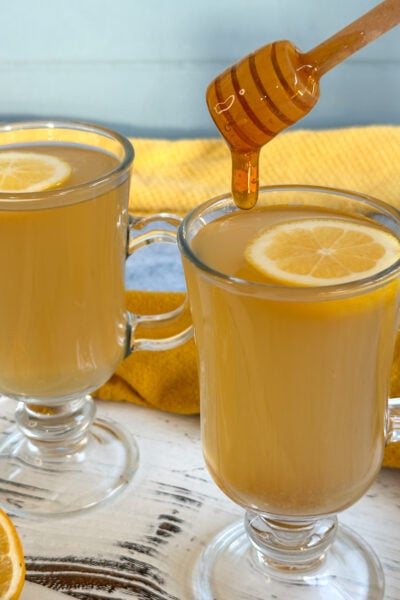 slow cooker lemon honey and ginger drink with honey drizzled in