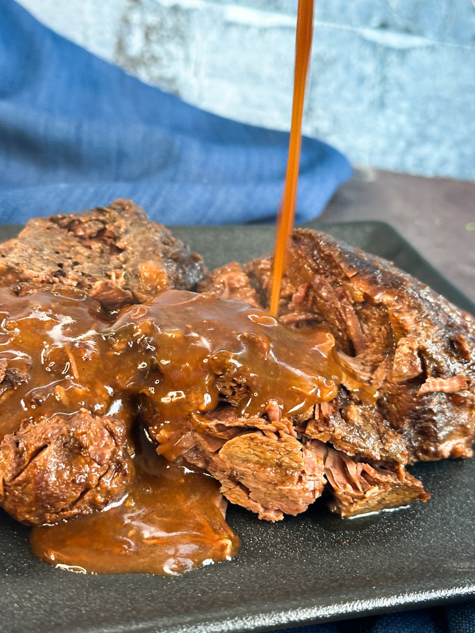 gravy being poured over slow cooker beef cheeks