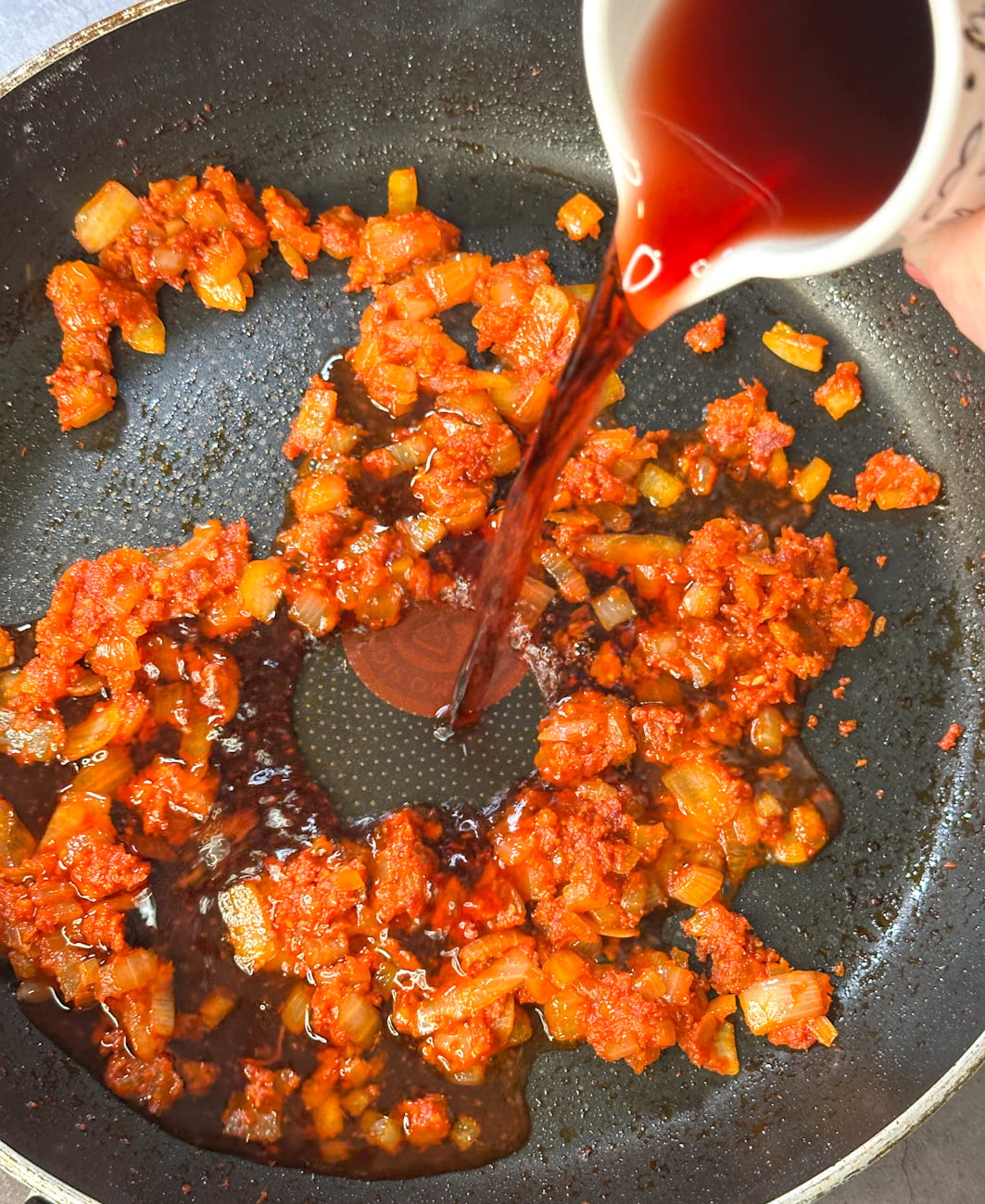 Pour in the red wine to deglaze the pan