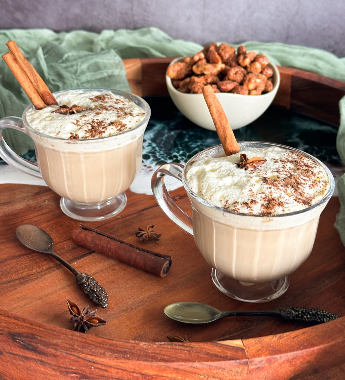 Slow cooker spiced chai in glass mugs with cream and cinnamon sticks