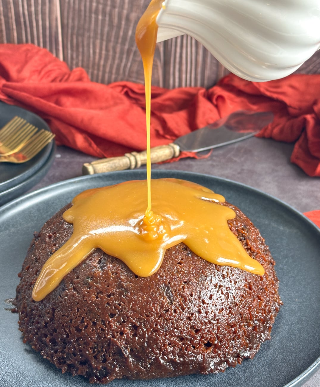 Pouring sauce over a sticky date pudding made in the slow cooker